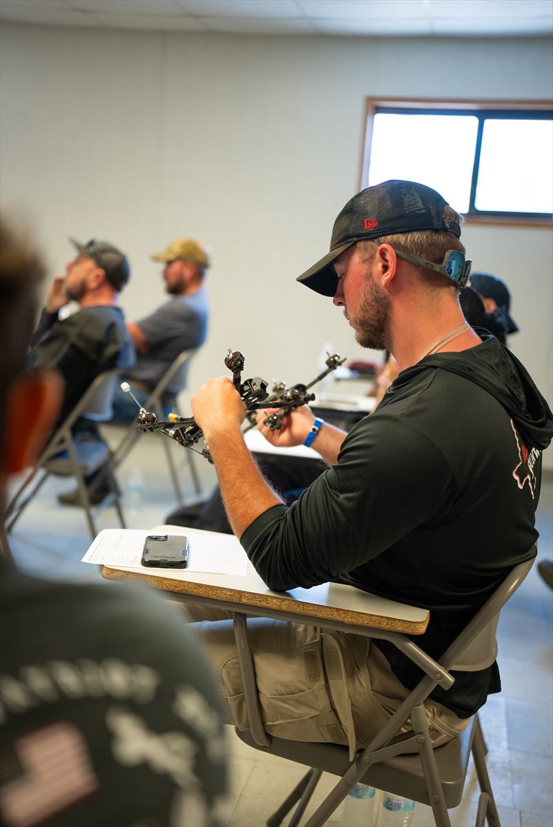 Students handling FPV drone equipment during training